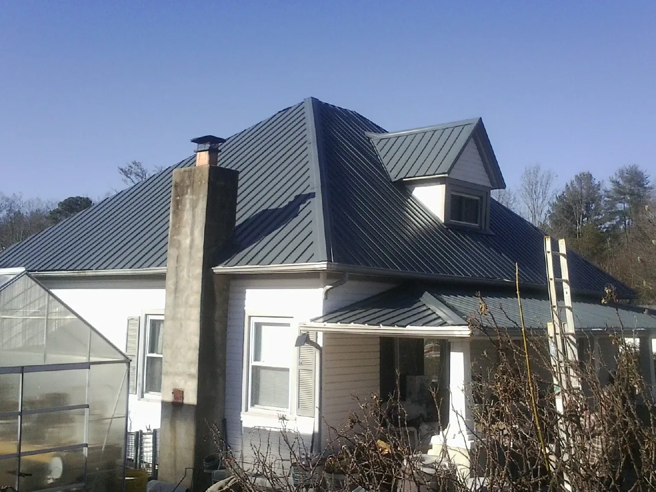 Dark blue standing seam metal roof on a white farmhouse with dormer — Slate & Tile Roof Repair by Roofing Brothers in Rappahannock Academy