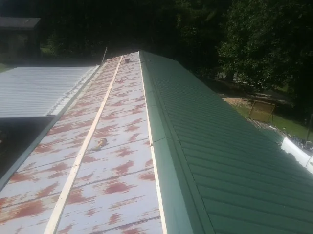 Old rusted panels beside newly installed green metal roofing — Wind Damage Roof Repair by Roofing Brothers in Rappahannock Academy