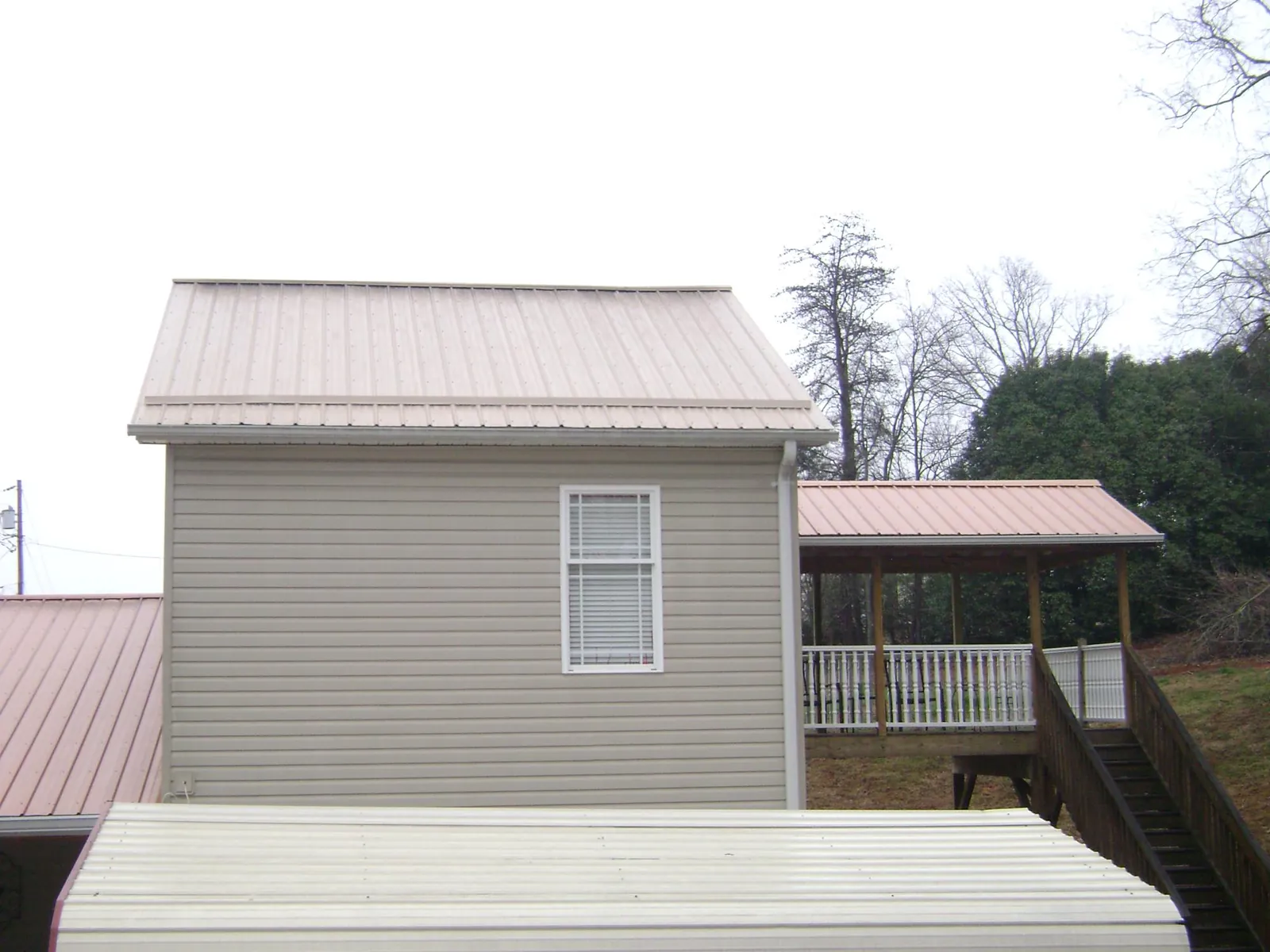 Tan metal roofs on a two story addition and attached porch, from a Roof Replacement job in Rappahannock Academy