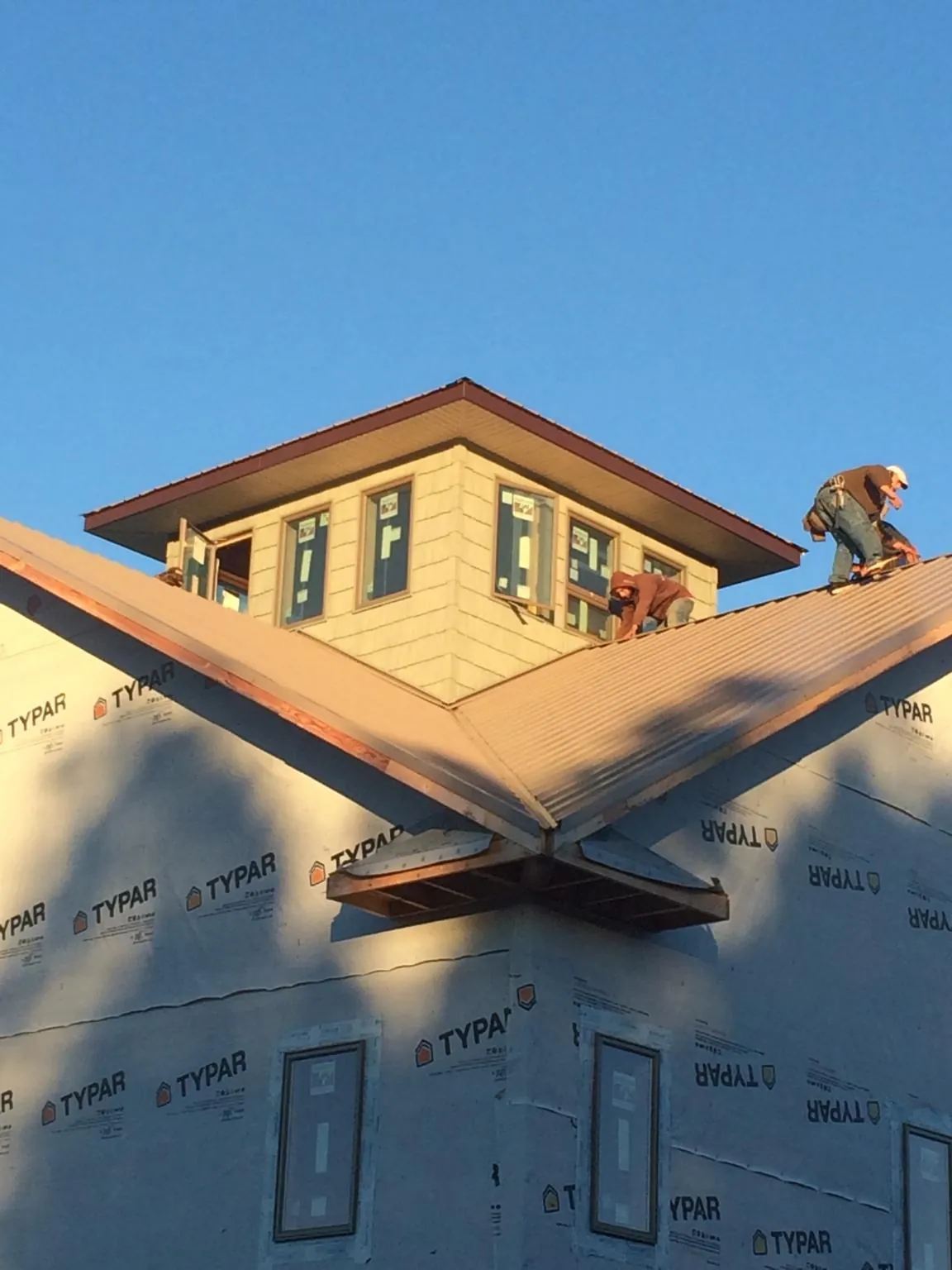 Roofers working around a rooftop cupola on a new metal roof at sunset — Roof Waterproofing in Rappahannock Academy by Roofing Brothers